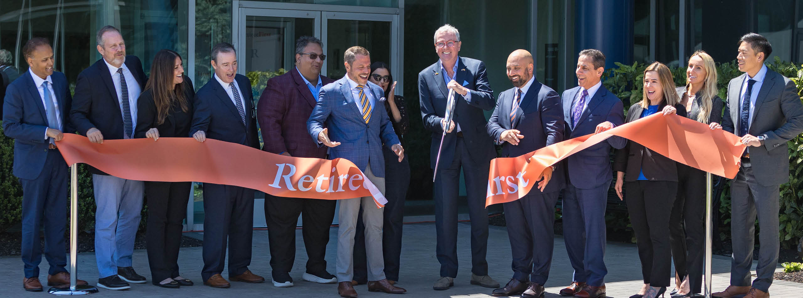 New Jersey Governor Phil Murphy and the RetireeFirst team cutting a ribbon to open a new building