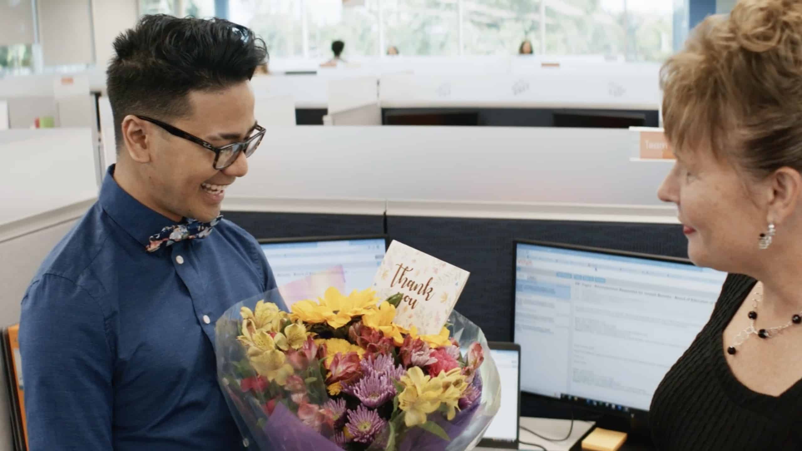 Employee getting a delivery of flowers with a thank you note